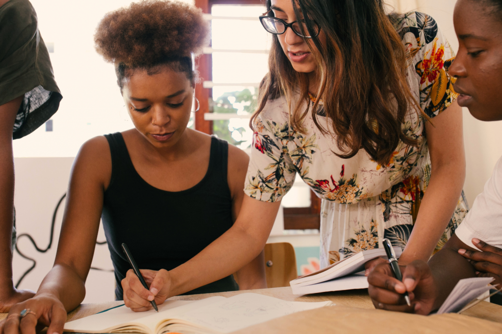 Equipo de trabajo de una organización sin fines de lucro escribiendo cartas a mano para una campaña navideña de recaudación de fondos por correo.