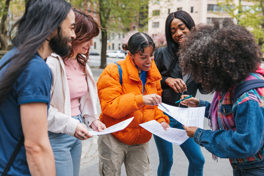Five diverse people from a nonprofit organization smiling and talking together outside during a collaborative moment.